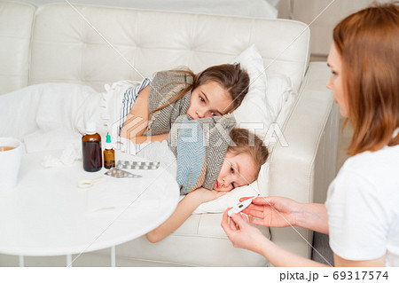 mother holding thermometer, little daughter sick 69317574