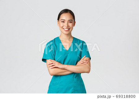 Covid-19, healthcare workers, pandemic concept. Confident smiling asian doctor, female nurse in scrubs standing determined, cross arms chest over white background. Doctor ready for shift in clinic Covid-19, healthcare workers, pandemic concept. Confident smiling asian doctor, female nurse in scrubs standing determined, cross arms chest over white background. Doctor ready for shift in clinic 69318800