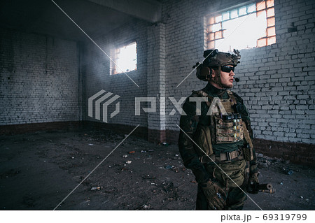 Front view close up of caucasian soldier with a rifle stand guard securing territory looking around. 69319799