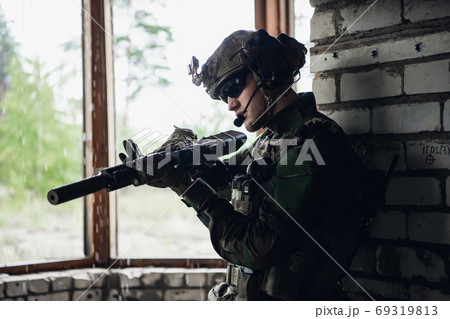 Weapon inspection while waiting on a spot. Military man checks his assault rifle preparing for operation. Weapon inspection while waiting on a spot. Military man checks his assault rifle preparing for operation. 69319813