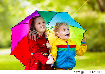 Kids playing in the rain under colorful umbrella 69321013