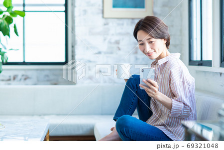 リビングでスマホを見るミドルの女性 リビングでスマホを見るミドルの女性 69321048