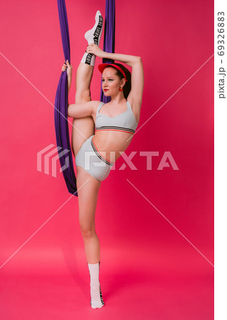 Full length body size view portrait cute pretty flexible sporty young womant gymnast in retro swim suit holds on air silk stretch out in splits over pink vivid background Full length body size view portrait cute pretty flexible sporty young womant gymnast in retro swim suit holds on air silk stretch out in splits over pink vivid background 69326883