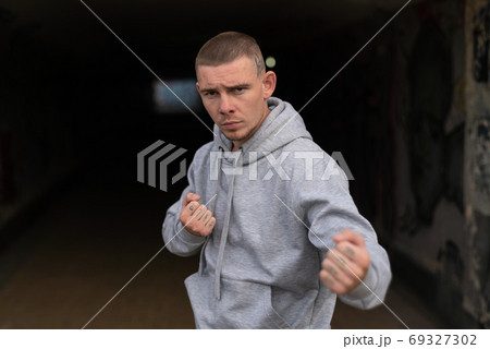 A bully guy in a light sports jacket with a hood 69327302