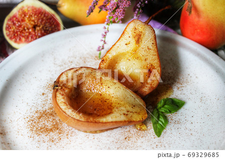 Baked pears in syrup on a white plate with a mint leaf close-up 69329685