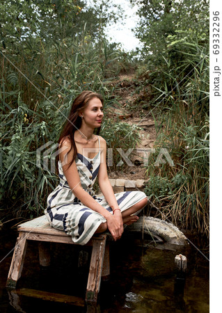 Beautiful young caucasian woman in dress having rest on the nature. 69332296