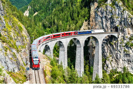Passenger train crossing the Landwasser Viaduct in Switzerland 69333786