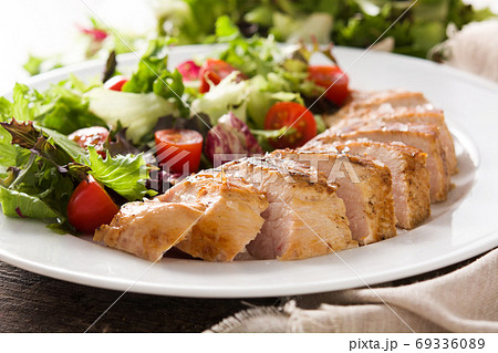 Grilled chicken breast with vegetables on a plate on wooden table. 	 69336089