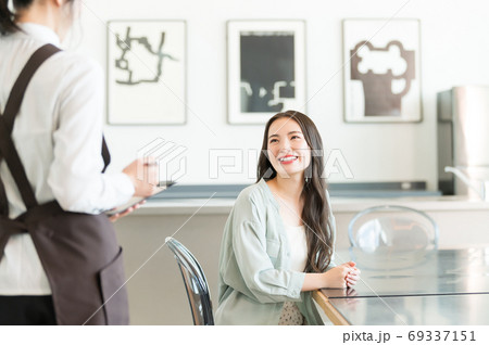 カフェで注文をする若い女性と店員 69337151