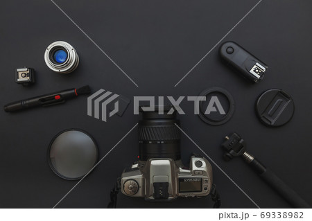 Photographer workplace with dslr camera system, camera cleaning kit, lens and camera accessory on dark black table background. Hobby travel photography concept. Flat lay top view copy space. Photographer workplace with dslr camera system, camera cleaning kit, lens and camera accessory on dark black table background. Hobby travel photography concept. Flat lay top view copy space. 69338982