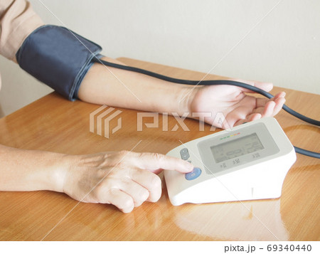 Middle aged women measuring her blood pressure and heart rate with automatic blood pressure monitor at home. Healthcare and medical concept. 69340440