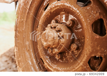 Wheel closeup in a countryside landscape with a muddy road. 69342009