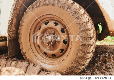Wheel closeup in a countryside landscape with a muddy road. 69342013