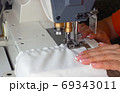 A woman sews on an industrial flat-seam sewing machine. Soft focus 69343011