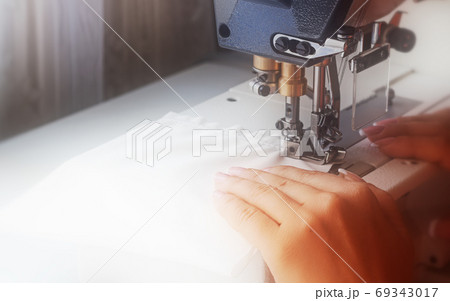 A woman sews on an industrial flat-seam sewing machine. Soft focus A woman sews on an industrial flat-seam sewing machine. Soft focus 69343017