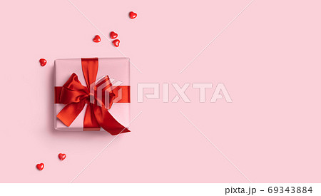 Pink gift box with red bow on pink background with red hearts around. Holiday web banner. Top view. Flat lay. Copy space Pink gift box with red bow on pink background with red hearts around. Holiday web banner. Top view. Flat lay. Copy space 69343884