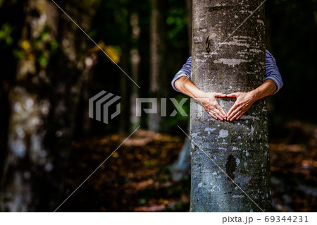 woman hand embracing a tree in the forest - nature loving, fight 69344231