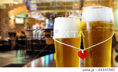 Two glasses of beer for lovers with red heart. Pub interior background. 69345985