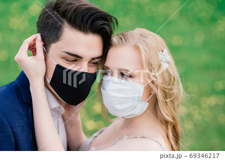Young couple walking in medical masks in park during quarantine on wedding day. 69346217