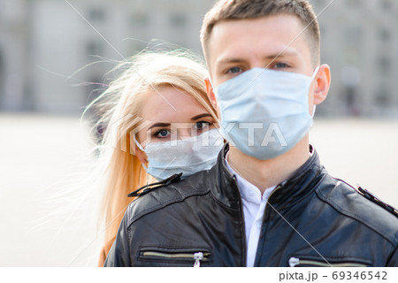 Young couple in love in protective medical mask on face outdoor at street. 69346542