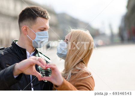 Young couple in love in protective medical mask on face outdoor at street. 69346543
