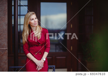 Young beautiful blonde in a red dress in the city. A business woman goes to work. Female businessman.  69347610