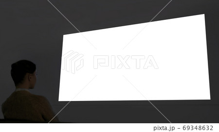 Woman looking at large blank white wall screen - cinema mock up Woman looking at large blank white wall screen - cinema mock up 69348632