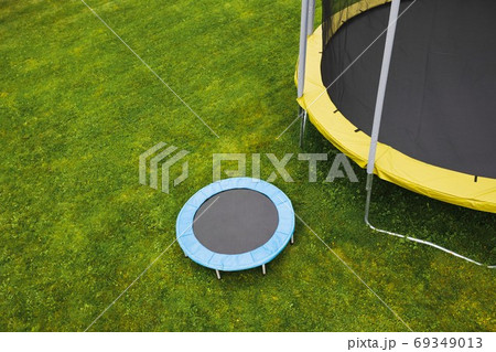 small trampoline near big one with round mat, size comparison, green lawn background small trampoline near big one with round mat, size comparison, green lawn background 69349013