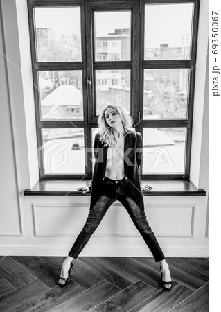 blonde girl in black clothes sit on window. blonde girl in black clothes sit on window. 69350067