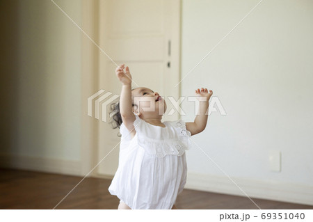 両手を上げて何かを掴もうとする赤ちゃんの写真素材