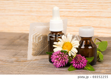 chamomile and clover tea and essential oil in small bottles 69352255