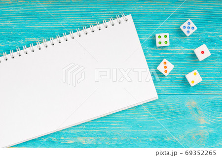 blank notepad with colorful dices over turquoise wooden table 69352265