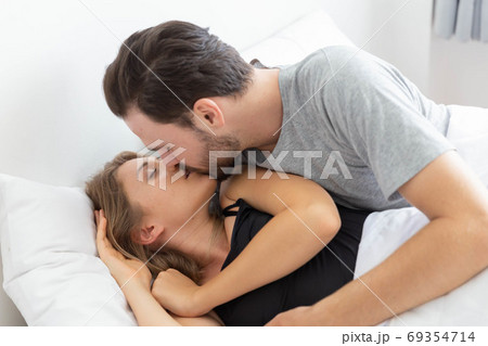 Caucasian couple kiss on bed in bedroom 69354714