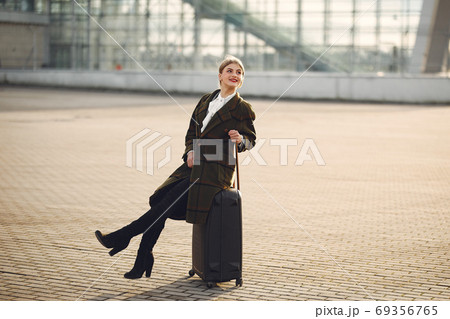 Woman with suitcase standing by the airport 69356765