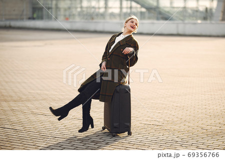 Woman with suitcase standing by the airport 69356766