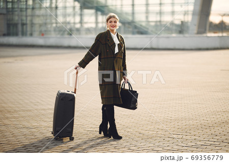 Woman with suitcase standing by the airport Woman with suitcase standing by the airport 69356779