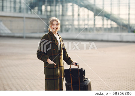 Woman with suitcase standing by the airport Woman with suitcase standing by the airport 69356800