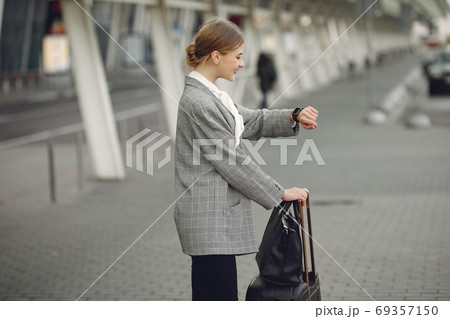 Woman with suitcase standing by the airport Woman with suitcase standing by the airport 69357150
