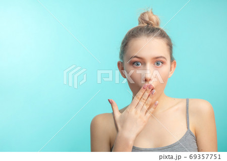 young attractive woman with hair knot staring at camera with shoked expression 69357751