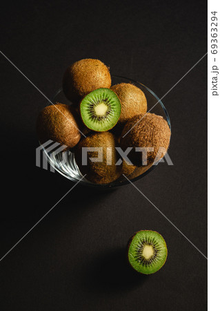 Kiwi fruits half sliced in glass bowl on dark background Kiwi fruits half sliced in glass bowl on dark background 69363294