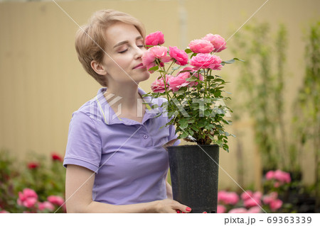 Beautiful young woman with roses posing in garden Beautiful young woman with roses posing in garden 69363339