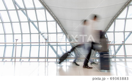 A people with luggage walking in motion blur on white corridor with large windows. A people with luggage walking in motion blur on white corridor with large windows. 69363883
