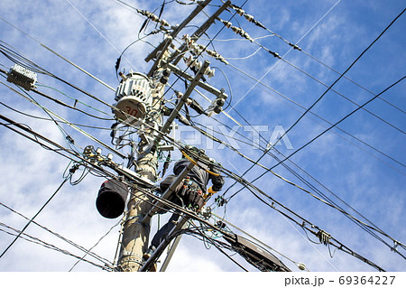 働く人＿青空を背景に電柱に上って作業する人 69364227