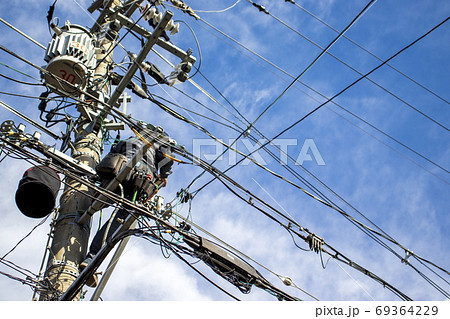 働く人＿青空を背景に電柱に上って作業する人 69364229