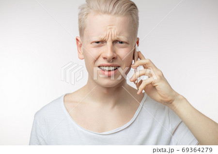 Annoyed male with frowned face recieving unpleasant news on mobile phone. Annoyed male with frowned face recieving unpleasant news on mobile phone. 69364279