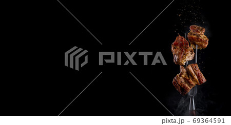 Fork with pieces of delicious barbecued meat on black background. banner 69364591