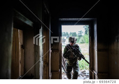 Front view close up of caucasian soldier with a rifle stand guard securing territory looking around. 69364728