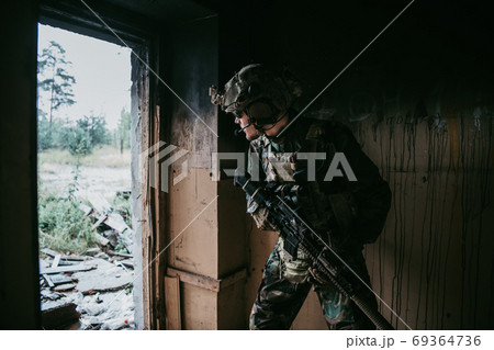 Soldier in full US MARSOC armed with assault rifle run through the abandoned building. Military clash. 69364736