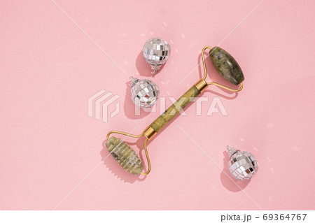 Guasha green natural gemstone face roller on pink background. Anti aging self care tool. Guasha green natural gemstone face roller on pink background. Anti aging self care tool. 69364767