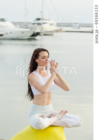 Young sportive woman is sitting on sea, marina pier and looking at horizon 69366133